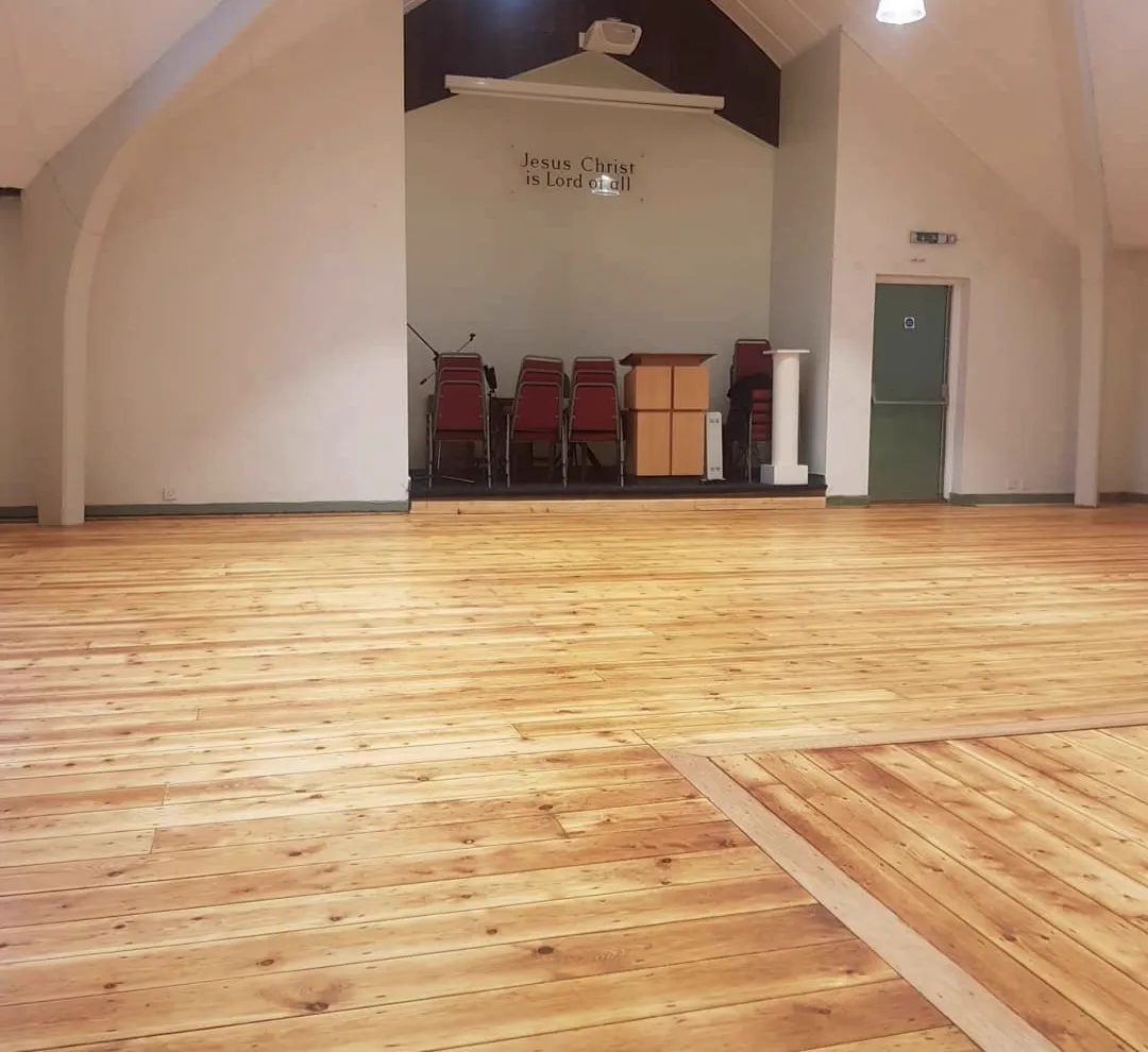 Freshly sanded golden pine floor in a church hall, restored by Howard Naish