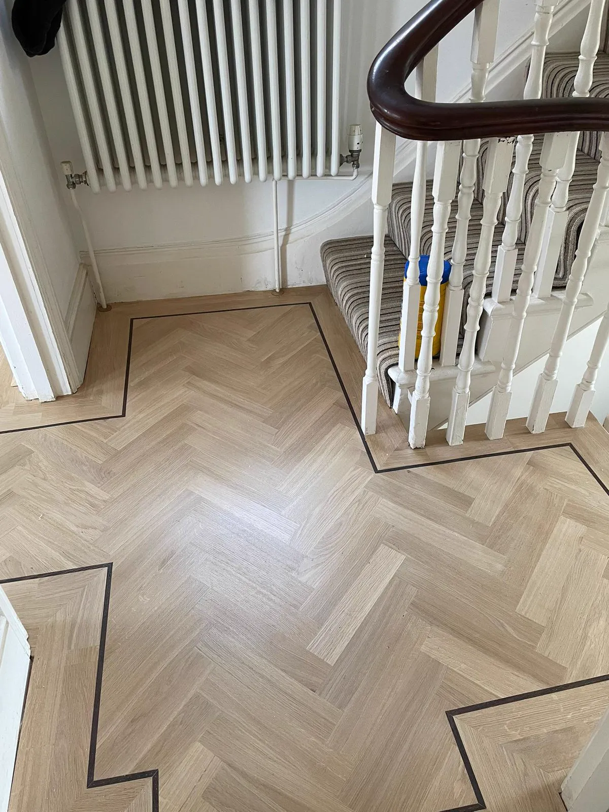 Herringbone parquet hallway with painted stairs in a Clapham SW4 home