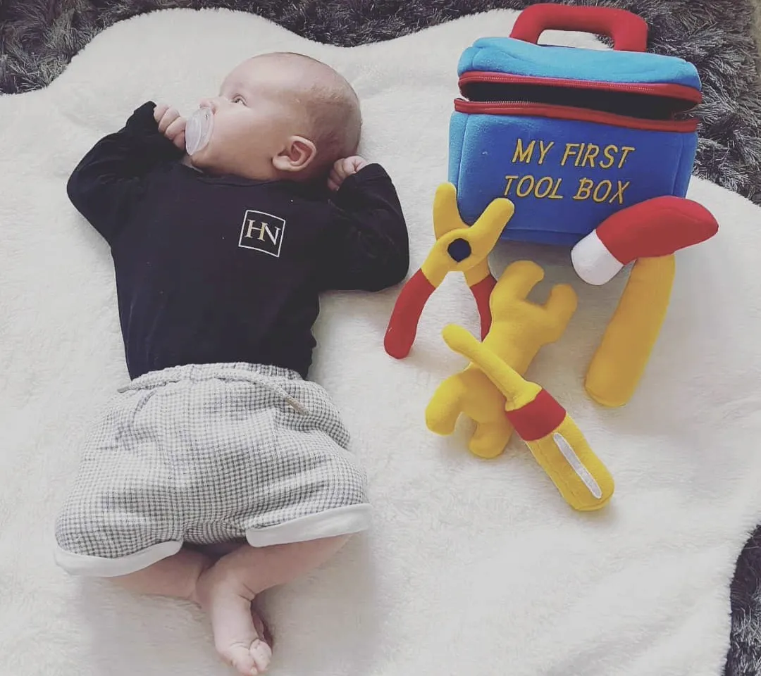 Dean's baby son Eddie in a Howard Naish babygro beside a My First Tool Box toy set