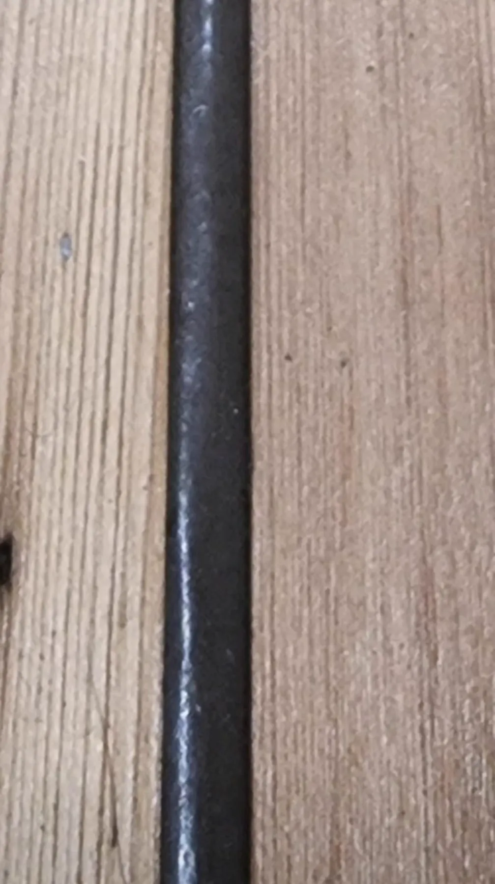 Dark flexible filler in the gap between original pine floorboards