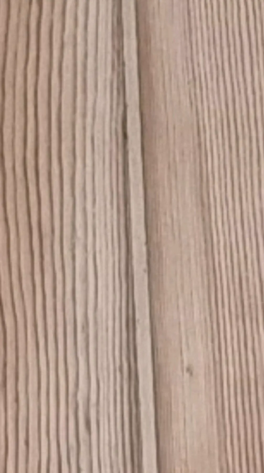 Light-toned flexible filler in the gap between pale pine floorboards