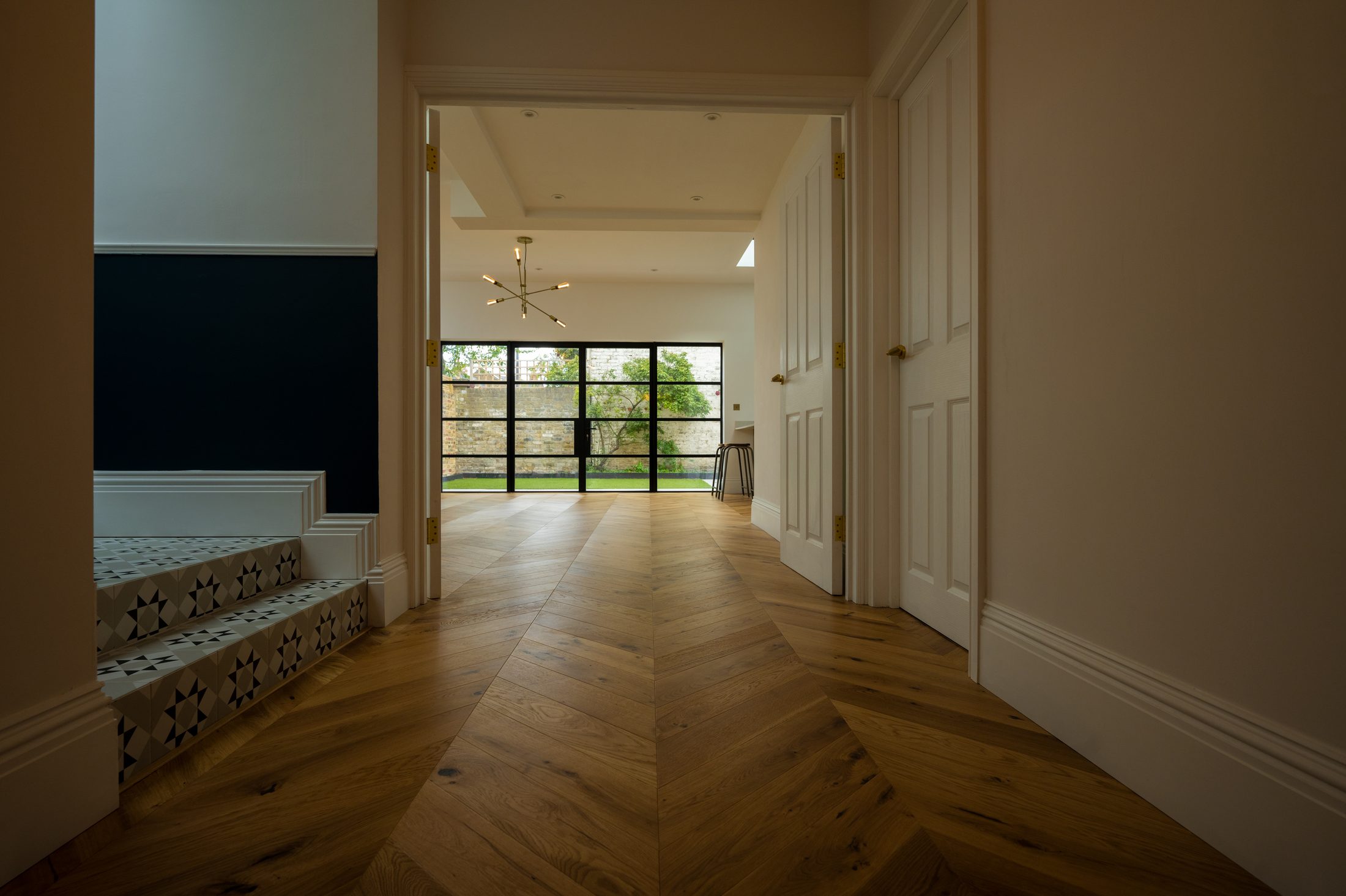 Chevron oak floor flowing through a South London home to garden doors, installed by Howard Naish