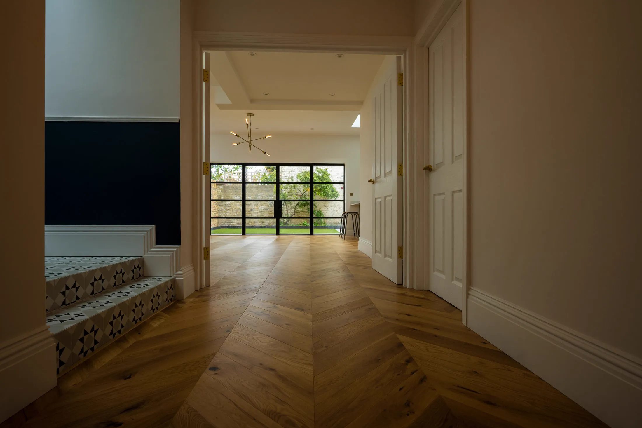 Chevron oak floor flowing through a South London home to garden doors, installed by Howard Naish