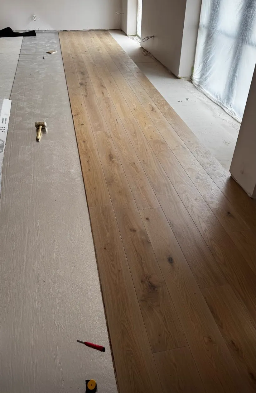 First rows of wide engineered oak planks being fitted over prepared underlay by Howard Naish