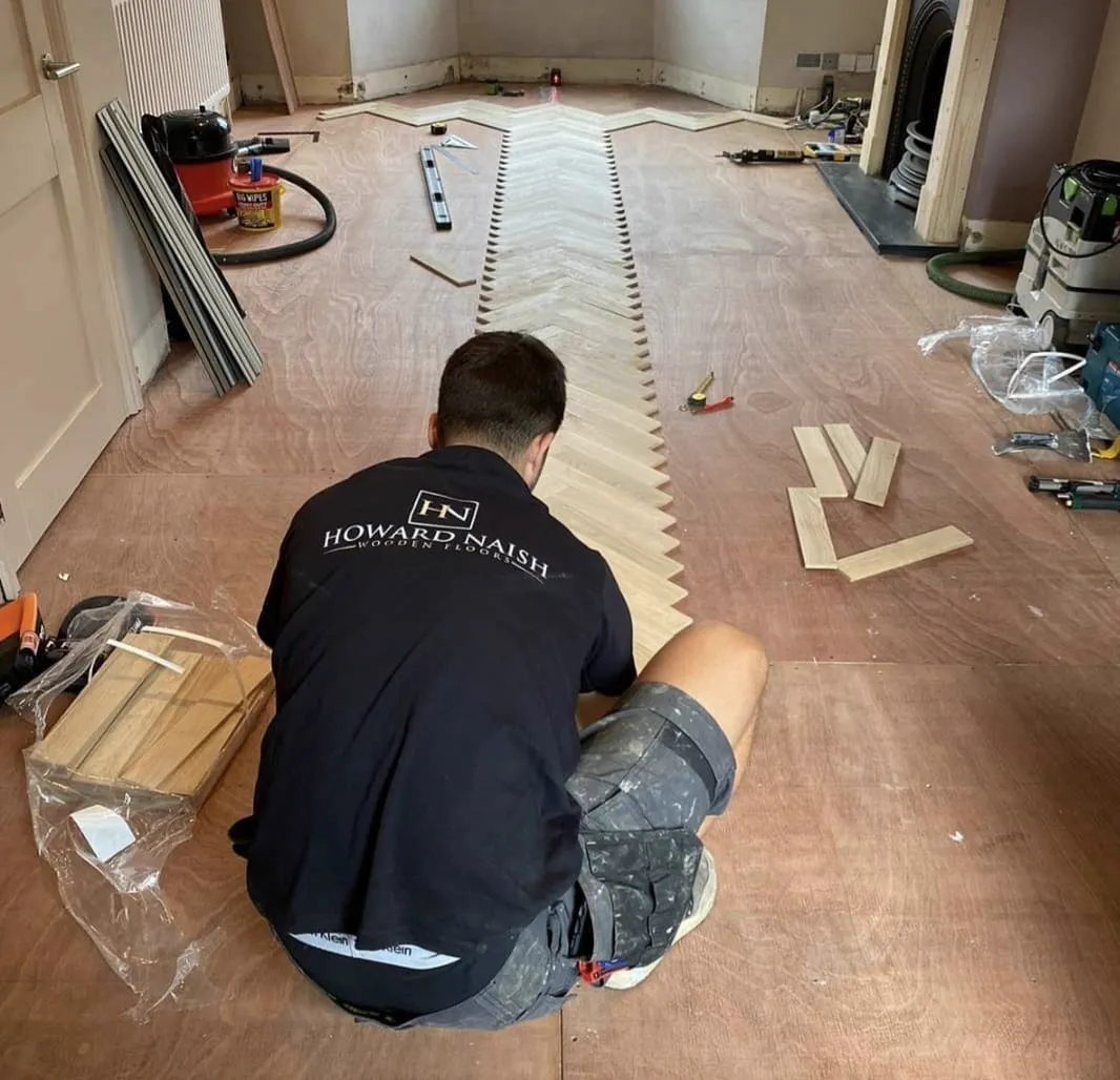 Luke Howard laying an oak herringbone floor in his Howard Naish work shirt