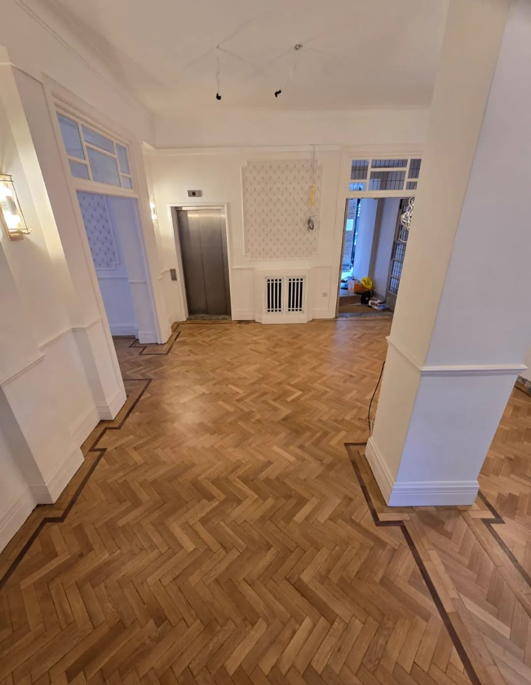 Restored herringbone parquet with a dark border in the reception of Redcliffe, a Chelsea apartment block, by Howard Naish