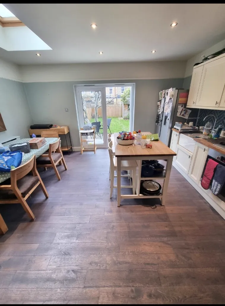 Dark stained wide boards flowing through a Sutton family kitchen-diner, sanded and coloured by Howard Naish