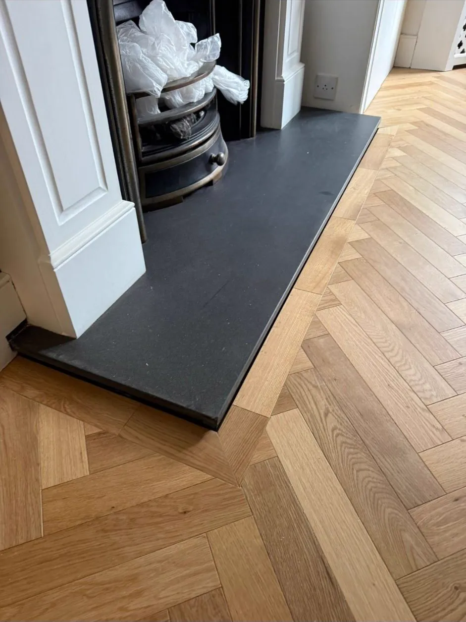 Herringbone parquet scribed neatly around a fireplace hearth by Howard Naish in Wimbledon